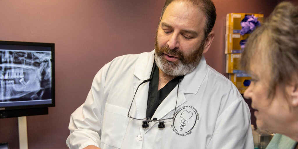 Doctor showing dental implant patient implant model within the office